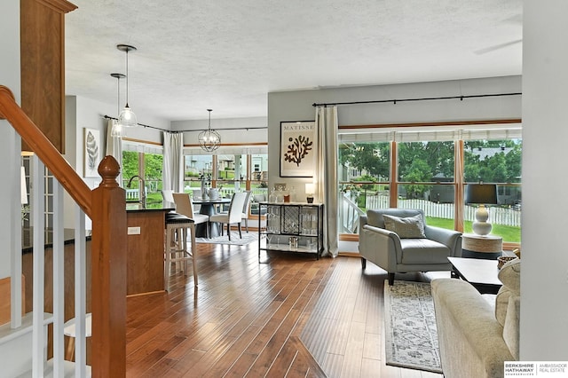 17534 Jefferson St, Omaha, NE 68135 - living room featuring dark wood-style floors, stairs, a textured ceiling, and a chandelier