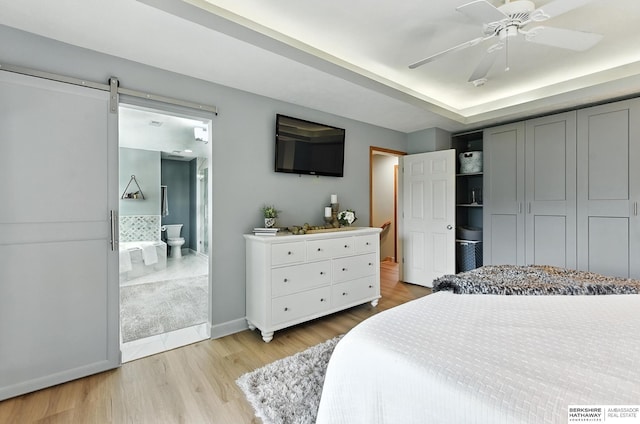 17534 Jefferson St, Omaha, NE 68135 - bedroom with light wood-style floors, a barn door, ensuite bathroom, and a ceiling fan