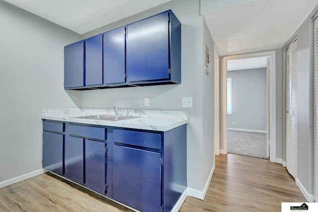 1207 B St, Lincoln, NE 68502 - kitchen featuring blue cabinets, light wood finished floors, and light countertops