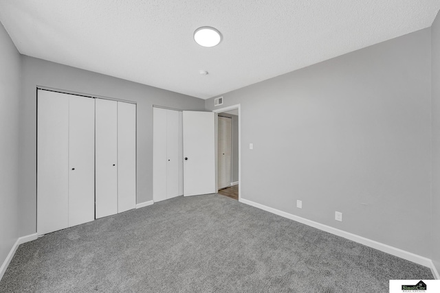 1207 B St, Lincoln, NE 68502 - unfurnished bedroom featuring carpet flooring, two closets, and a textured ceiling