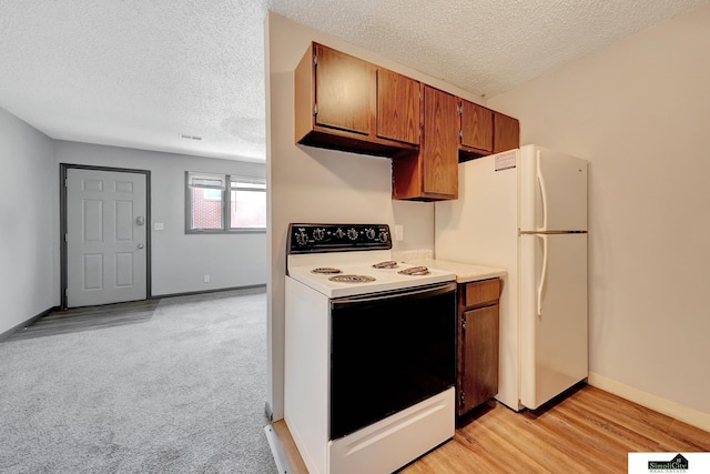 1207 B St, Lincoln, NE 68502 - kitchen with white appliances, a textured ceiling, brown cabinets, light countertops, and light wood-style flooring