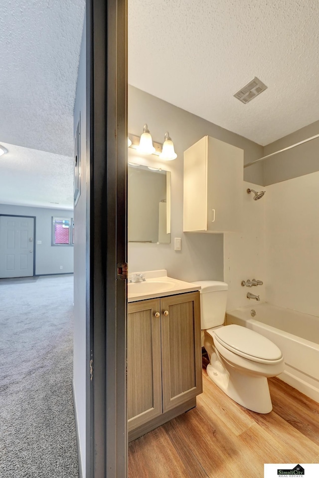 1207 B St, Lincoln, NE 68502 - bathroom with a textured ceiling, vanity, washtub / shower combination, and wood finished floors