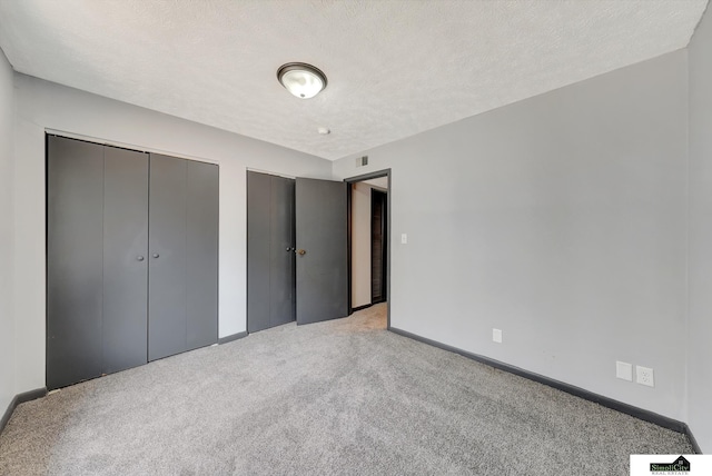 1207 B St, Lincoln, NE 68502 - unfurnished bedroom with multiple closets, light colored carpet, and a textured ceiling