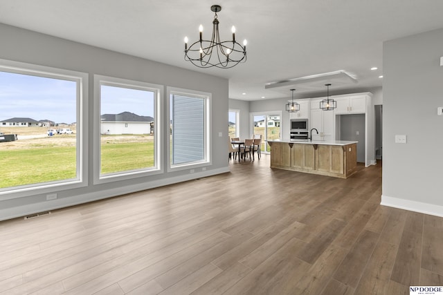 20976 Ogden St, Elkhorn, NE 68022 - kitchen with a chandelier, recessed lighting, an island with sink, light countertops, and wood finished floors