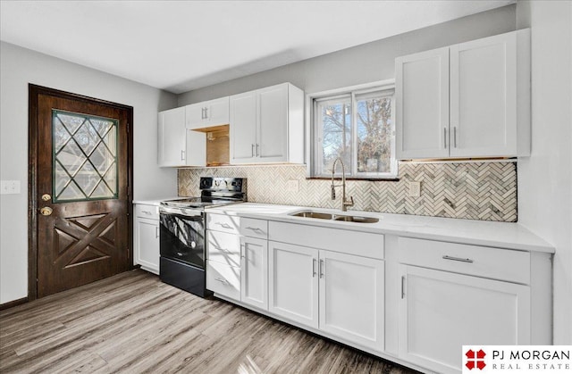 14030 Orchard Ave, Omaha, NE 68137 - kitchen featuring black range with electric cooktop, light countertops, white cabinetry, decorative backsplash, and light wood-style flooring