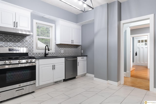3207 Castelar St, Omaha, NE 68105 - kitchen with appliances with stainless steel finishes, under cabinet range hood, dark countertops, light marble finish floors, and backsplash