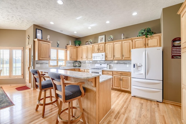 223 N Lakeview Way, Ashland, NE 68003 - kitchen featuring white appliances, a textured ceiling, light wood finished floors, a kitchen island, and a kitchen bar