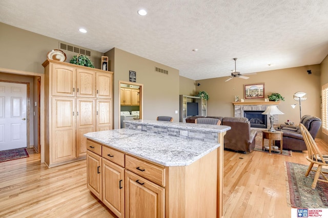 223 N Lakeview Way, Ashland, NE 68003 - kitchen with a textured ceiling, light wood-type flooring, a fireplace, a ceiling fan, and washer and clothes dryer