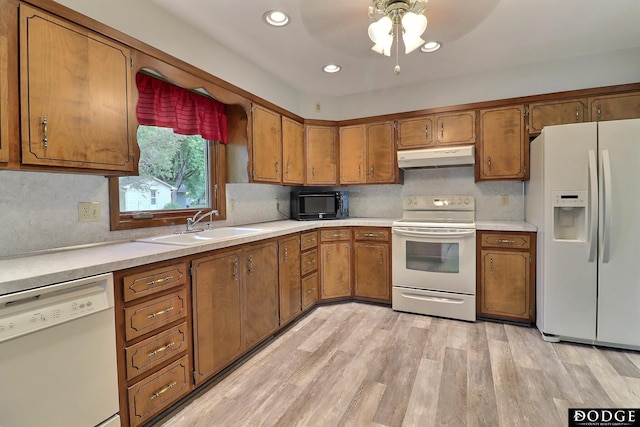 2204 Bramblewood Ln, Fremont, NE 68025 - kitchen with white appliances, under cabinet range hood, brown cabinetry, light wood-style flooring, and recessed lighting