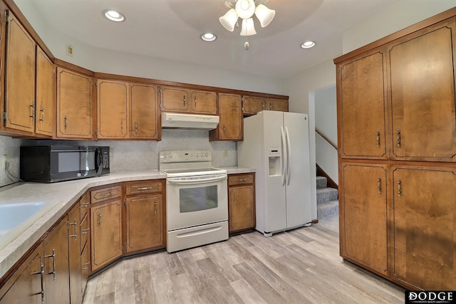 2204 Bramblewood Ln, Fremont, NE 68025 - kitchen featuring white appliances, under cabinet range hood, brown cabinets, light wood finished floors, and light countertops