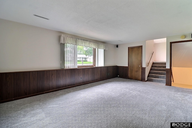 2204 Bramblewood Ln, Fremont, NE 68025 - spare room with stairway, wainscoting, carpet floors, a textured ceiling, and wooden walls