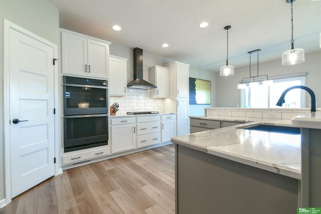 5017 N 209th St, Elkhorn, NE 68022 - kitchen with wall chimney exhaust hood, decorative backsplash, light wood-style flooring, white cabinetry, and decorative light fixtures