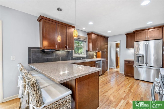 12079 Westover Rd, Omaha, NE 68154 - kitchen featuring appliances with stainless steel finishes, tasteful backsplash, light wood-type flooring, a peninsula, and light stone countertops