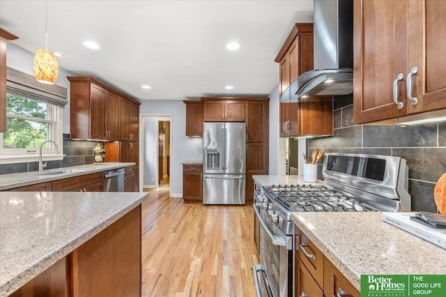 12079 Westover Rd, Omaha, NE 68154 - kitchen featuring appliances with stainless steel finishes, wall chimney exhaust hood, brown cabinetry, light wood-type flooring, and decorative backsplash