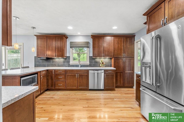 12079 Westover Rd, Omaha, NE 68154 - kitchen with stainless steel appliances, light wood-type flooring, decorative backsplash, pendant lighting, and brown cabinets