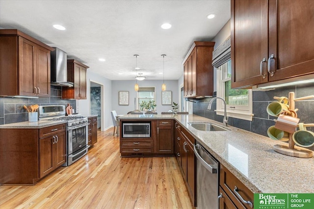 12079 Westover Rd, Omaha, NE 68154 - kitchen with stainless steel appliances, wall chimney exhaust hood, a peninsula, light wood finished floors, and backsplash