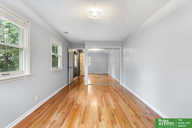 12079 Westover Rd, Omaha, NE 68154 - unfurnished bedroom with multiple windows, light wood finished floors, a closet, and a textured ceiling