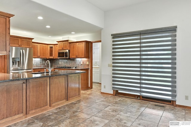 10505 S 179th St, Omaha, NE 68136 - kitchen featuring appliances with stainless steel finishes, brown cabinetry, backsplash, dark stone counters, and recessed lighting