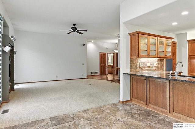 10505 S 179th St, Omaha, NE 68136 - kitchen with brown cabinets, light carpet, a ceiling fan, decorative backsplash, and dark stone countertops