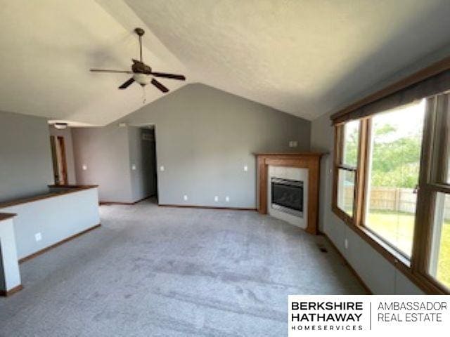 220 Orchard Pl, Hickman, NE 68372 - unfurnished living room featuring lofted ceiling, a ceiling fan, a fireplace, and light carpet