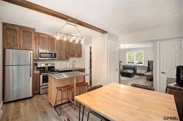 1913 Winnie Dr Unit 5, Bellevue, NE 68005 - kitchen with appliances with stainless steel finishes, light wood finished floors, a breakfast bar, a kitchen island, and light countertops