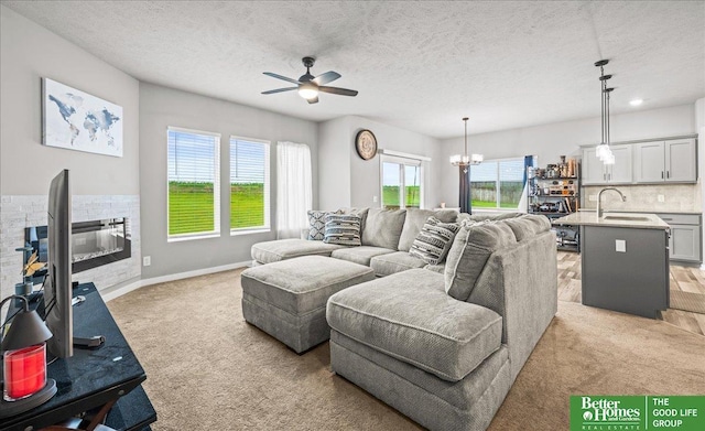 13512 S 55th St, Papillion, NE 68133 - living room with light carpet, ceiling fan, a chandelier, a textured ceiling, and a glass covered fireplace
