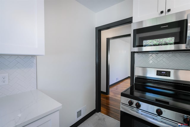 3018 S 42nd St, Lincoln, NE 68506 - kitchen with stainless steel appliances, backsplash, white cabinetry, light stone countertops, and light marble finish floors