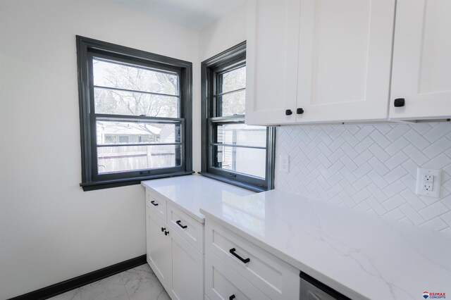 3018 S 42nd St, Lincoln, NE 68506 - kitchen with white cabinetry, light stone countertops, light marble finish floors, and backsplash