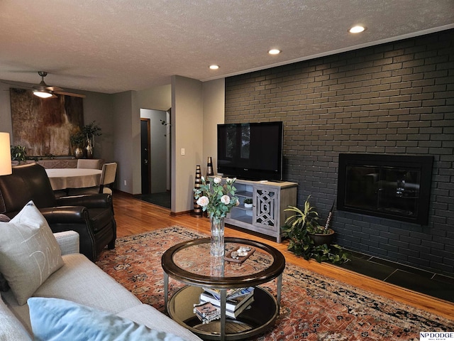 11821 Shirley St, Omaha, NE 68144 - living area with wood finished floors, a textured ceiling, a brick fireplace, and recessed lighting