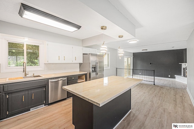 1409 Nelson Ln, Fremont, NE 68025 - kitchen with appliances with stainless steel finishes, white cabinetry, light wood-type flooring, and decorative light fixtures