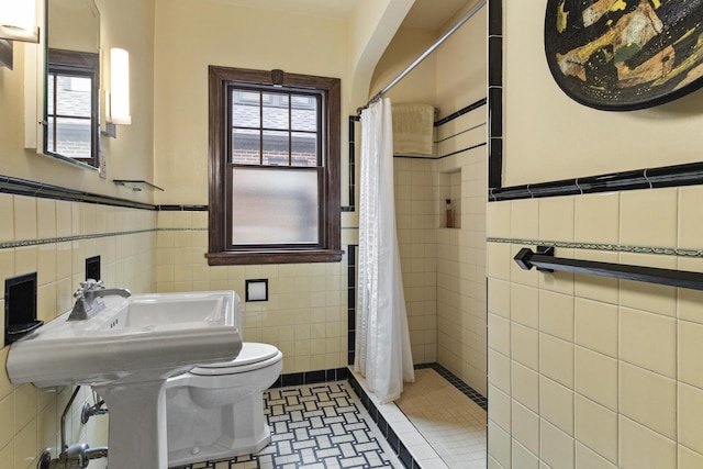 6024 Poppleton Ave, Omaha, NE 68106 - bathroom featuring tile walls, healthy amount of natural light, wainscoting, a tile shower, and tile patterned floors