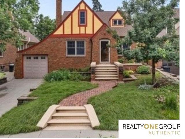 6024 Poppleton Ave, Omaha, NE 68106 - tudor-style house featuring driveway, a front yard, and an attached garage