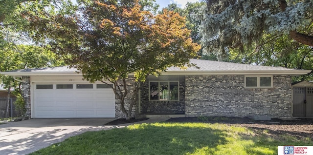 4211 S 36th St, Lincoln, NE 68506 - view of front of house featuring an attached garage, concrete driveway, brick siding, and a front yard