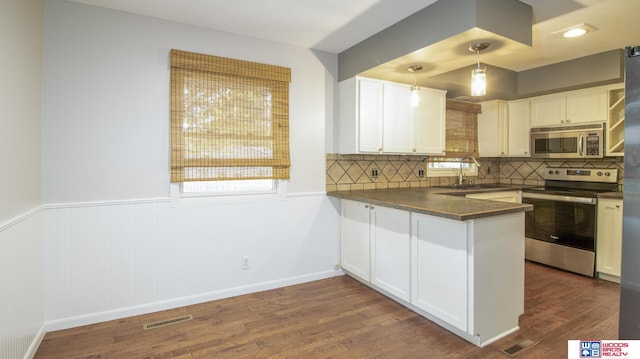 4211 S 36th St, Lincoln, NE 68506 - kitchen with stainless steel appliances, dark countertops, dark wood-style floors, white cabinetry, and wainscoting