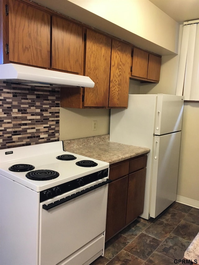 1321 D St, Lincoln, NE 68502 - kitchen featuring white appliances, under cabinet range hood, light countertops, tasteful backsplash, and stone finish floors