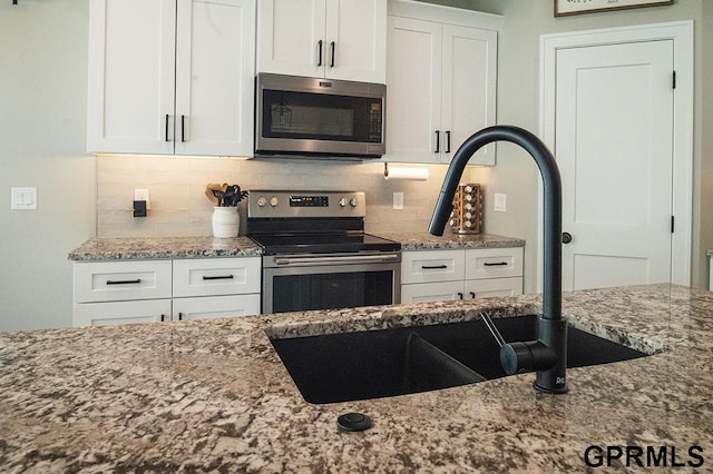 1600 W Avalanche Rd, Lincoln, NE 68521 - kitchen featuring stainless steel appliances, light stone countertops, white cabinetry, and backsplash