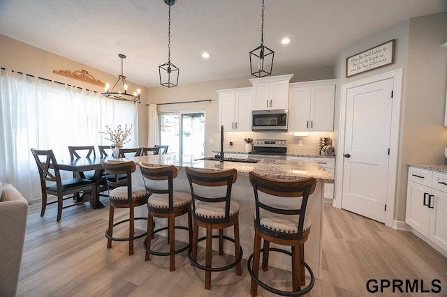 1600 W Avalanche Rd, Lincoln, NE 68521 - kitchen featuring appliances with stainless steel finishes, light wood finished floors, a breakfast bar area, recessed lighting, and a kitchen island with sink