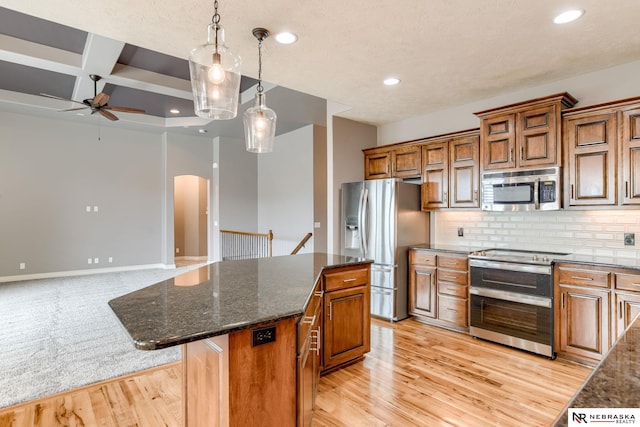 8023 S 193rd St, Gretna, NE 68028 - kitchen with stainless steel appliances, a ceiling fan, arched walkways, a kitchen island, and brown cabinetry