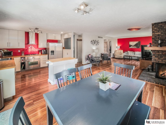 7533 Sherman St, Lincoln, NE 68506 - dining area with wood finished floors, a fireplace, and rail lighting