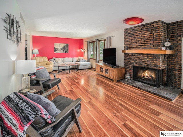 7533 Sherman St, Lincoln, NE 68506 - living room featuring wood finished floors, a textured ceiling, and a brick fireplace