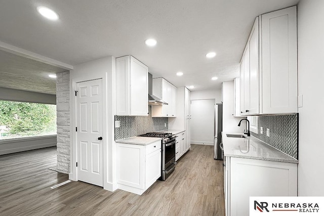 1113 S 94th St, Omaha, NE 68124 - kitchen with appliances with stainless steel finishes, wall chimney range hood, light wood-style flooring, white cabinetry, and recessed lighting