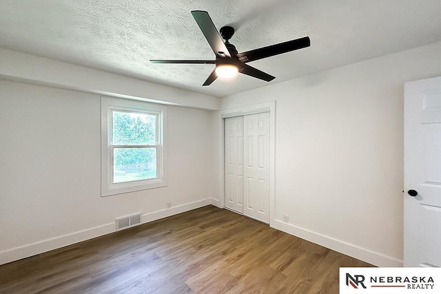 1113 S 94th St, Omaha, NE 68124 - unfurnished bedroom featuring dark wood-style flooring, a closet, a ceiling fan, and a textured ceiling