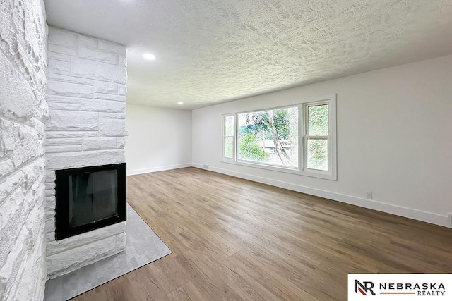 1113 S 94th St, Omaha, NE 68124 - unfurnished living room with a fireplace, wood finished floors, recessed lighting, and a textured ceiling