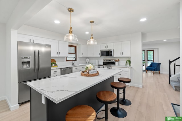 203 S 150th Cir, Omaha, NE 68154 - kitchen with appliances with stainless steel finishes, white cabinets, a kitchen bar, a center island, and light wood-type flooring