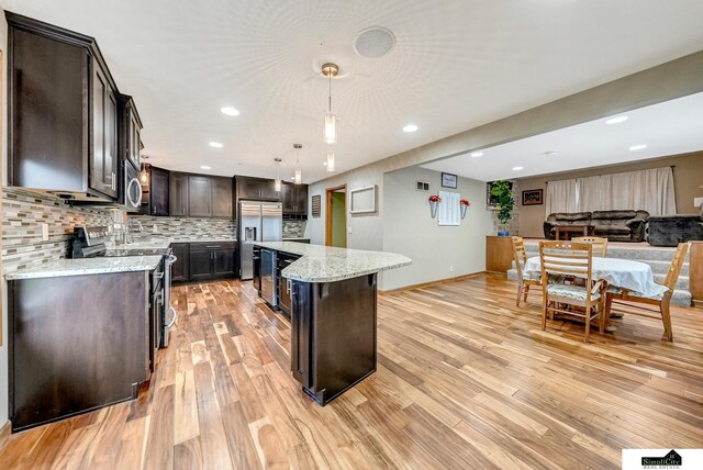 4721 Woodhaven Dr, Lincoln, NE 68516 - kitchen featuring stainless steel appliances, a center island, dark brown cabinets, backsplash, and light wood-type flooring