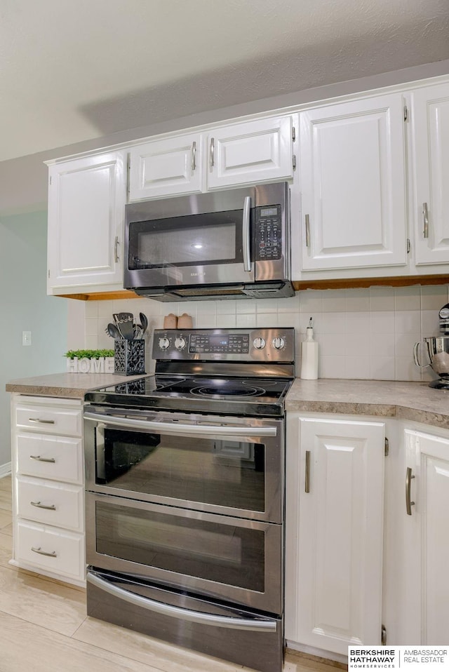534 Piedmont Dr, Omaha, NE 68154 - kitchen featuring appliances with stainless steel finishes, decorative backsplash, light countertops, and white cabinetry