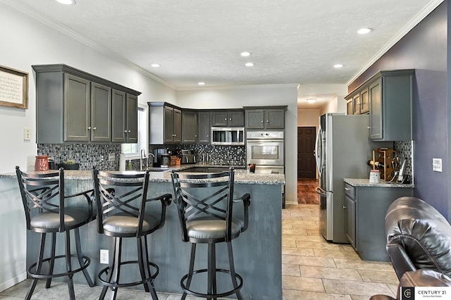 4806 Steavenson Loop, Blair, NE 68008 - kitchen with appliances with stainless steel finishes, a peninsula, backsplash, a kitchen bar, and recessed lighting