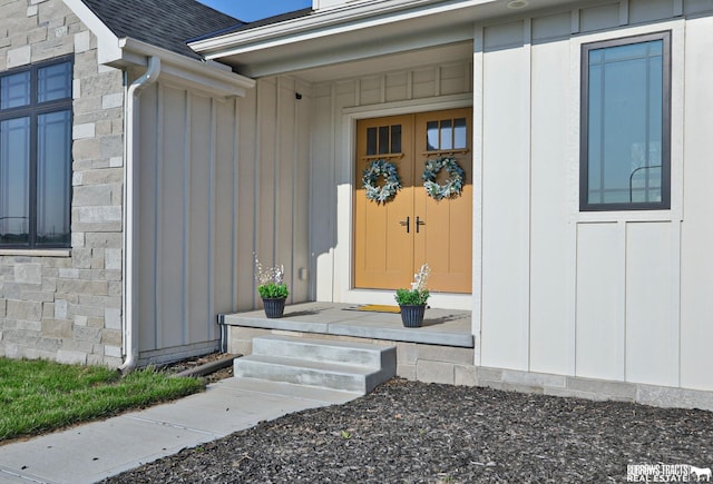 8150 S 185th St, Omaha, NE 68136 - view of exterior entry with board and batten siding, stone siding, and a shingled roof