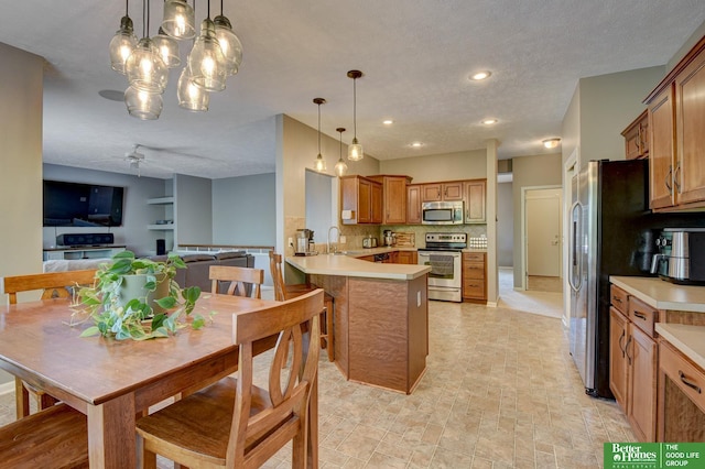 1608 Old Gaelic St, Bellevue, NE 68123 - kitchen featuring appliances with stainless steel finishes, decorative backsplash, a peninsula, decorative light fixtures, and recessed lighting