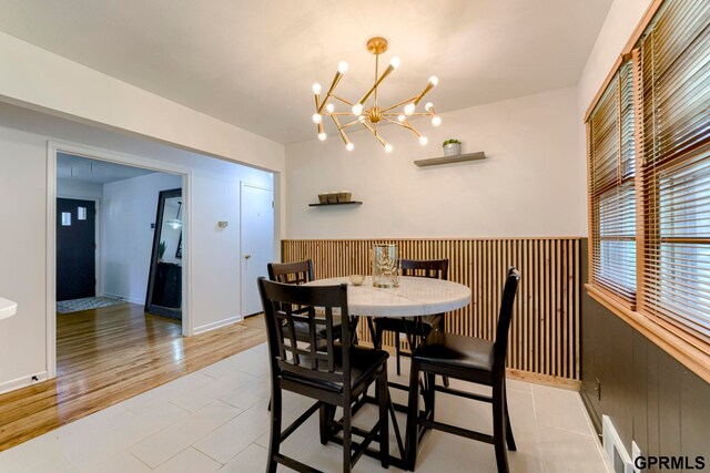 4509 Ridgeway Rd, Omaha, NE 68134 - dining area featuring a chandelier, wainscoting, wooden walls, and light tile patterned floors
